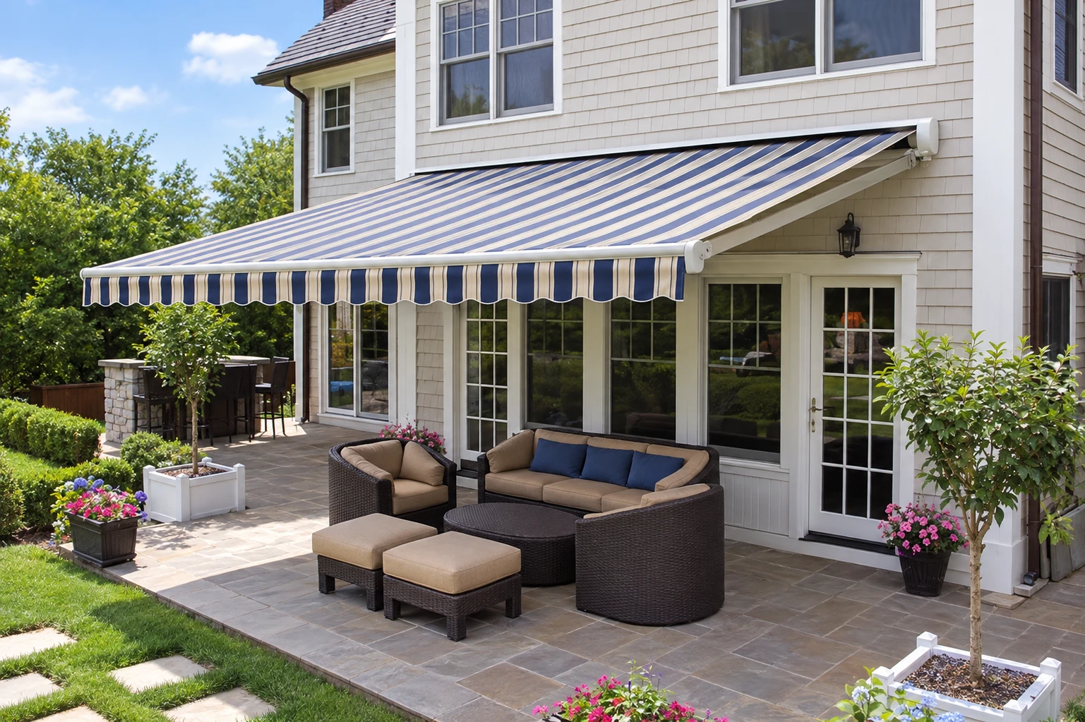Retractable striped awning shading a patio seating area beside a house