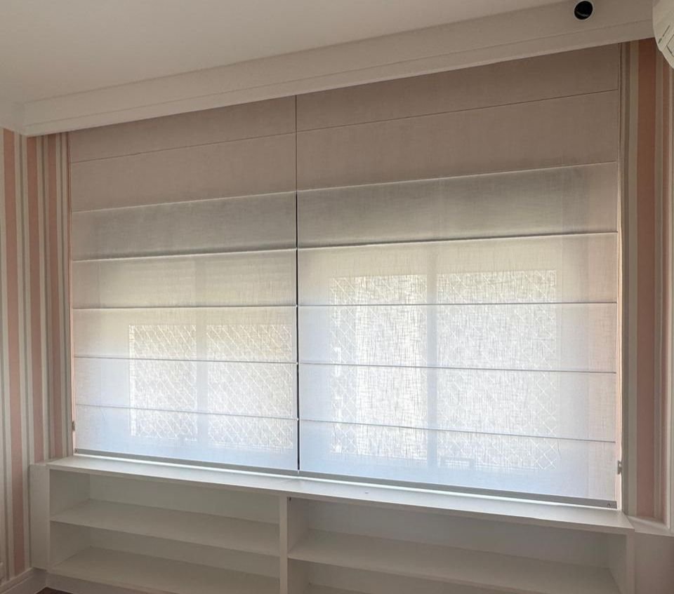 Sheer roman shade over a wide window above built-in shelves