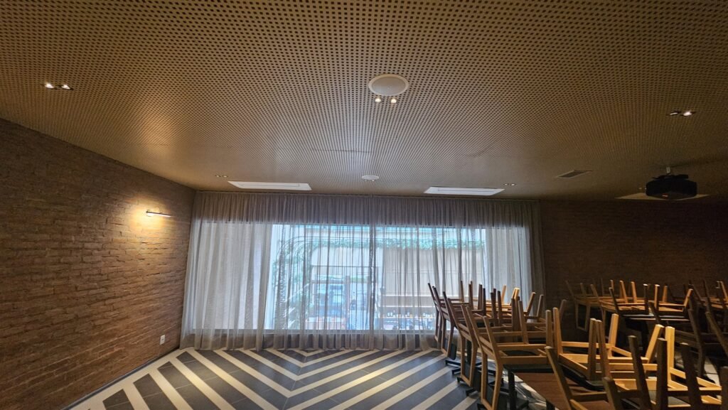 Meeting room with sheer curtains across a wide window and wood-slat ceiling