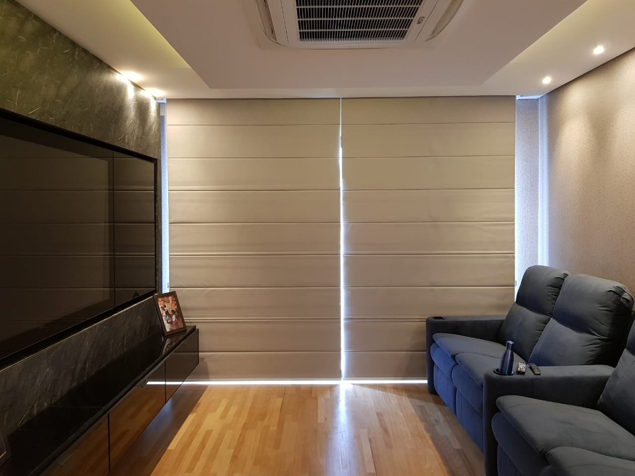 Window shades in a living room with a wall-mounted TV